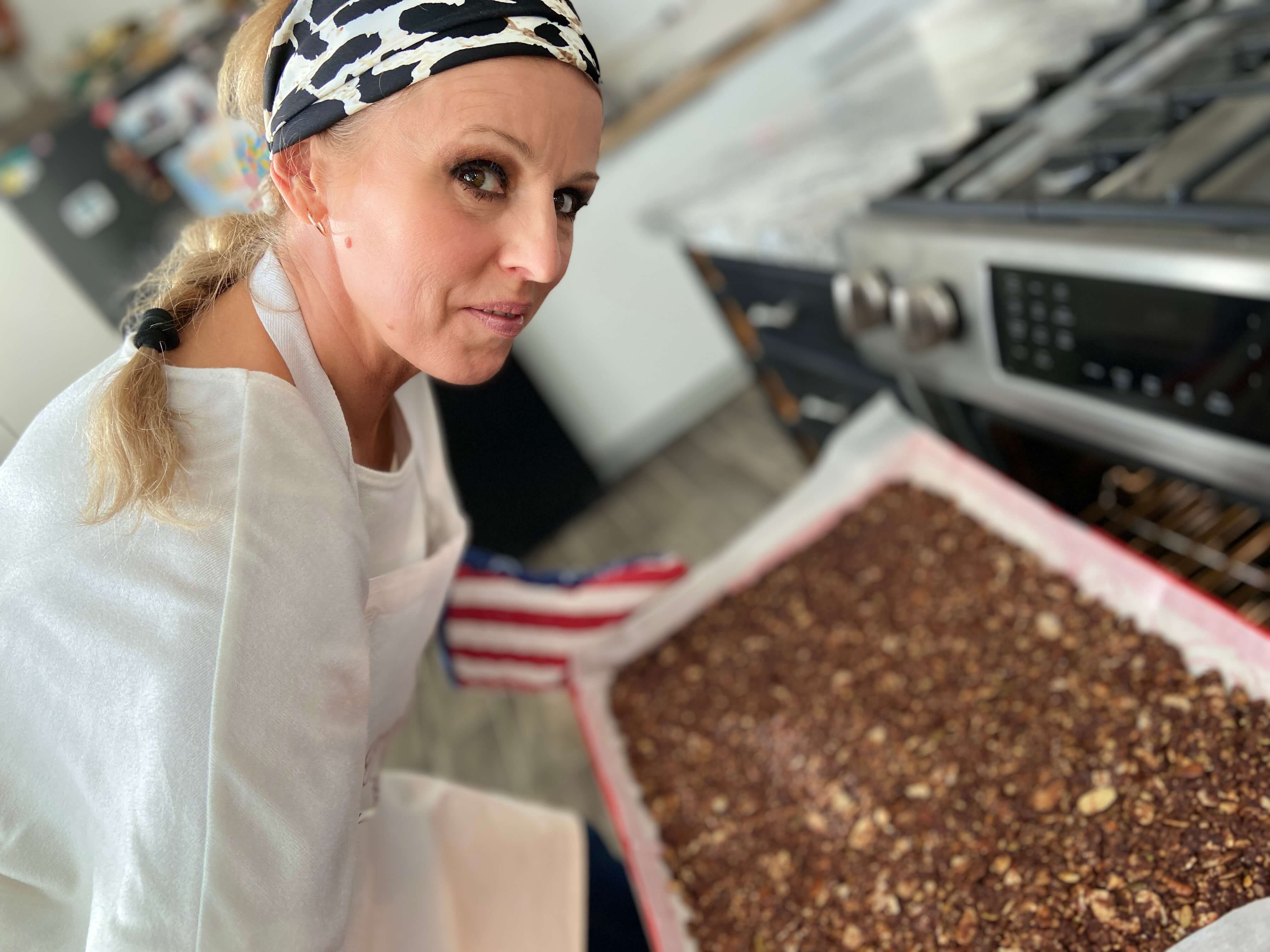 Photo of Judit Hodges, JuNula Just Nuts Granola CEO removing a batch of JuNula from the oven
