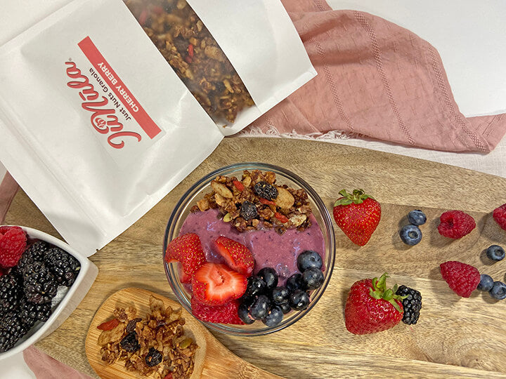 Photo of a bag of Cherry Berry JuNūla Just Nuts Granola with a bowl of Cherry Berry granola with yogurt and fresh berries