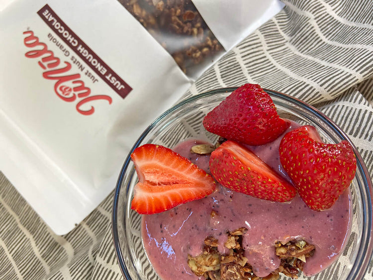 Photo of a bag of Just Enough Chocolate JuNūla Just Nuts Granola next to a bowl of granola with yogurt and fresh strawberries