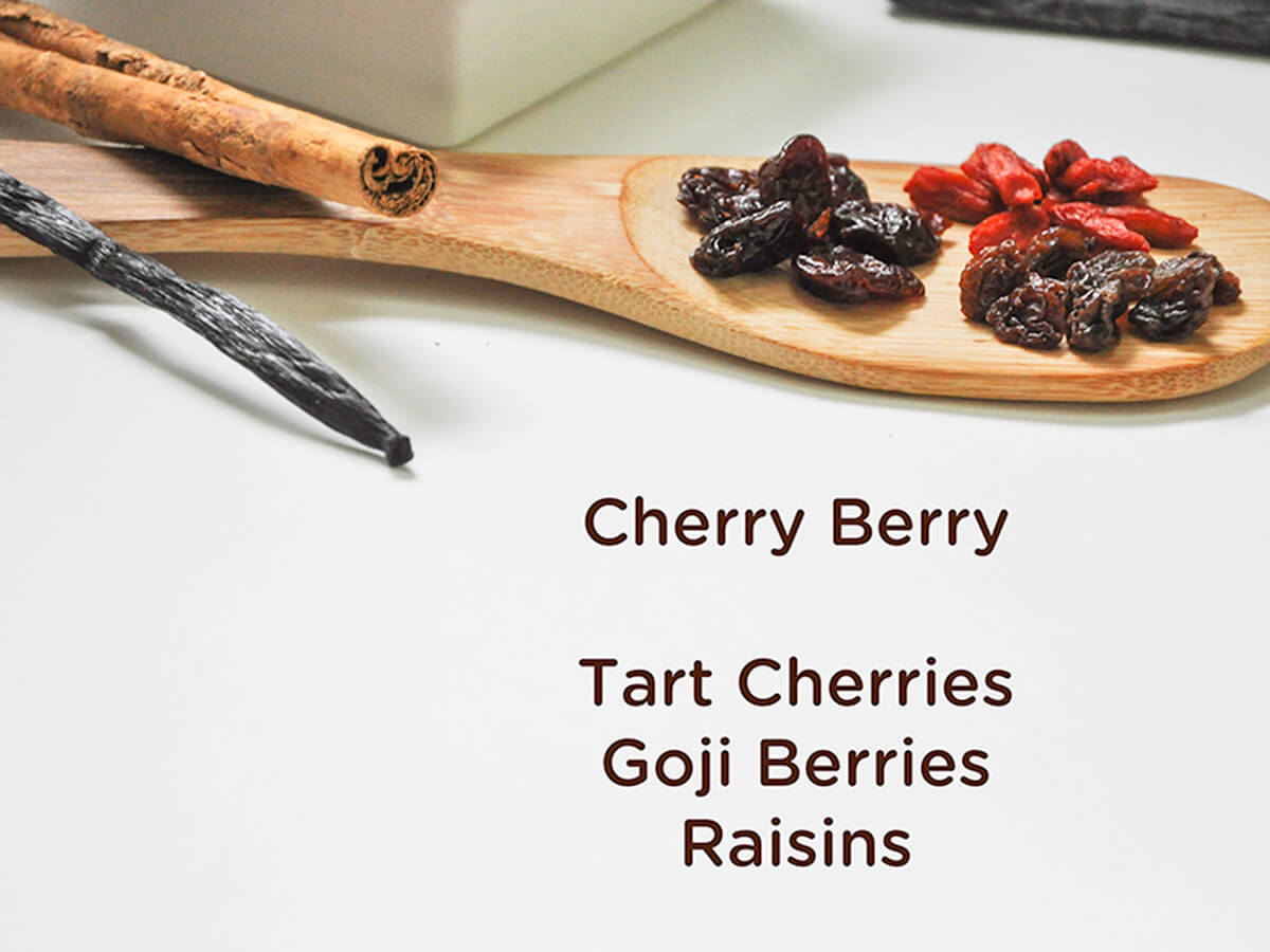 A photo of a vanilla bean, a cinnamon stick, dried tart cherries, goji berries, and raisins, all ingredients for Cherry Berry JuNūla Just Nuts Granola