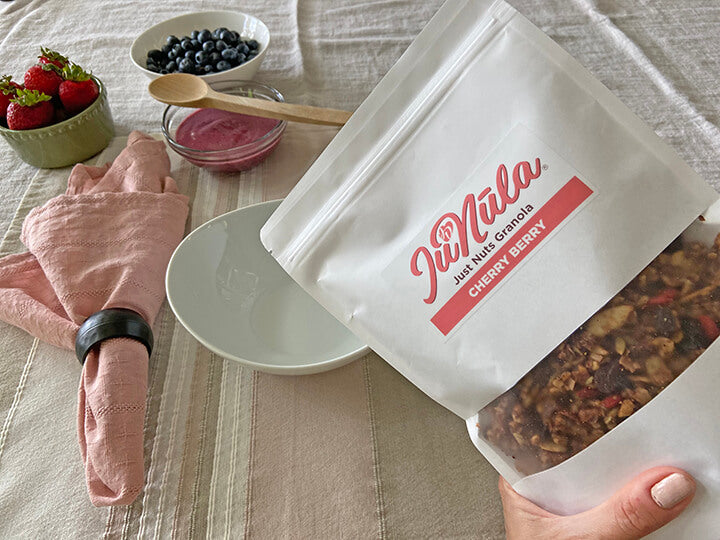 Photo of a bag of Cherry Berry JuNūla Just Nuts Granola ready to be poured into a bowl on a table