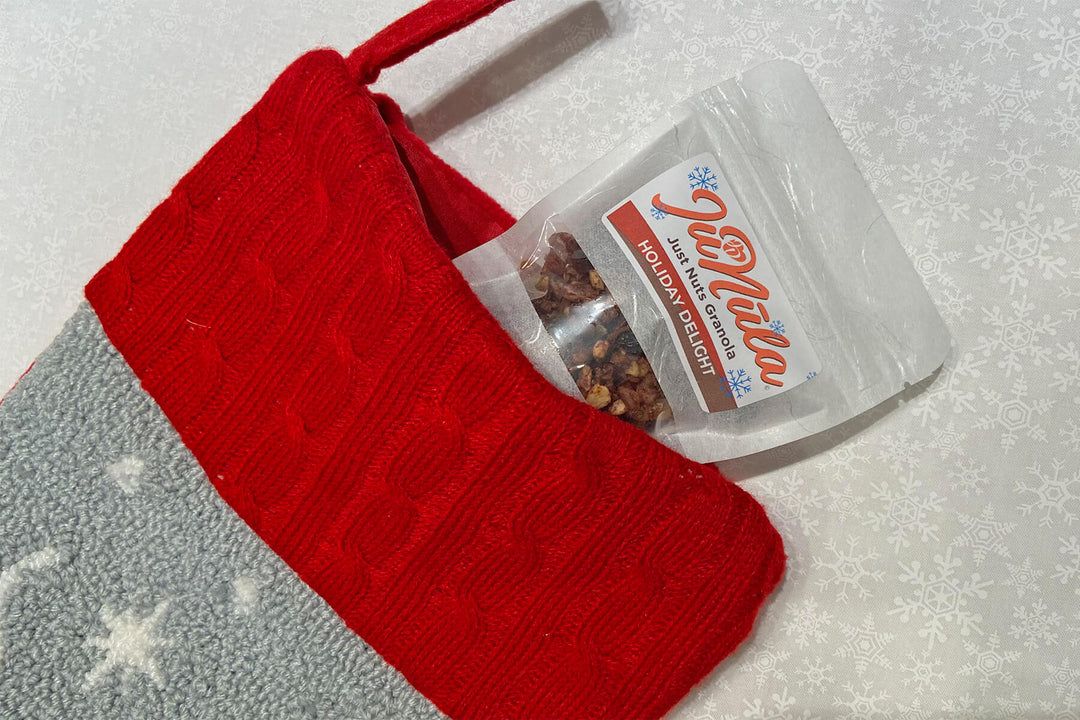 Photo of a 2oz bag of Holiday Delight JuNūla Just Nuts Granola peeking out of the top of a holiday stocking as a stocking stuffer